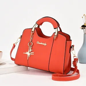 Sac à main élégant en cuir orange vif avec pendentif étoile et détails dorés brillants