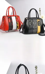 Detail of red and black glossy patent leather handbags with crocodile pattern texture