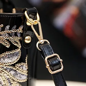 Elegant black patent leather handbag with wavy sequins and gold hardware detail