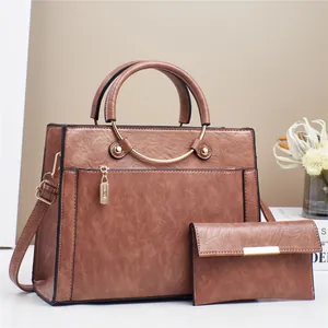 Brown leather tote bag and clutch set with gold hardware on a minimalist background