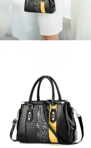 Close-up of faux snake and yellow croc pattern stitching on glossy crossbody bag