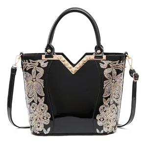 Elegant black patent leather handbag with floral sequin embroidery and a V-shaped rhinestone