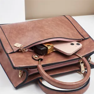 Detail view of tan synthetic leather handbag with golden hardware and round top handles