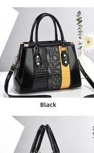 Detail of black glossy faux leather tote bag with yellow and grey crocodile pattern