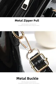Detail of glossy black patent leather bag featuring premium gold-toned zipper and metal hooks