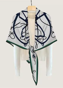 Détail d'une écharpe en maille blanche avec courbes bleues et bords verts
