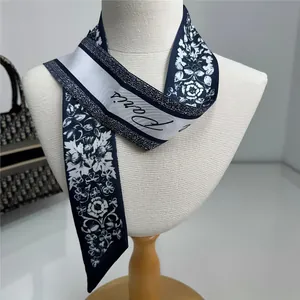 Détail d'un foulard en soie bleu marine avec fleurs et texte Paris noué sur un mannequin