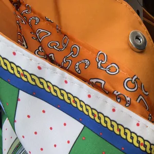 Detail view of orange leather handbag showing silk lining and silver magnetic buckle