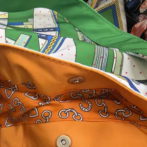Detail of magnetic buckle and orange fabric lining with classic horse-bit pattern