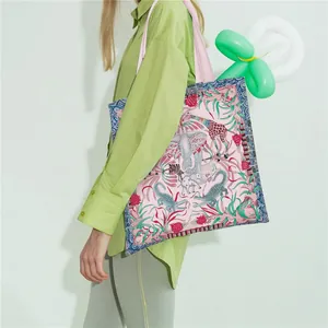 Model showcasing a large canvas tote bag with pink jungle animal prints and blue borders