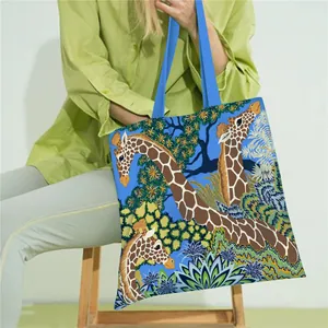 Artistic tote bag featuring giraffe and floral prints on a vibrant blue canvas background