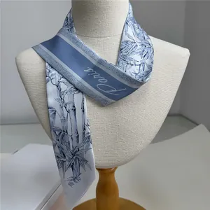 Detail view of a blue floral silk twilly with bamboo patterns and Paris script on a mannequin
