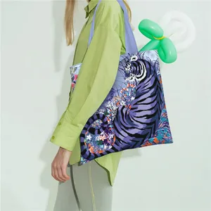Bolso tote de lona que muestra el gran estampado de tigre morado y flores en el hombro