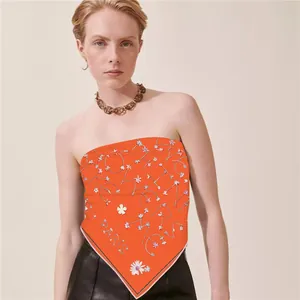 Vibrant orange silk scarf with floral print and Paris lettering worn as a chic top
