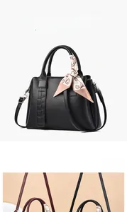 Close-up of black leather handbag with litchi texture and decorative silk scarf detail