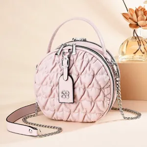 Detail of pink round bag featuring heart quilting, gold zipper, and clover charm