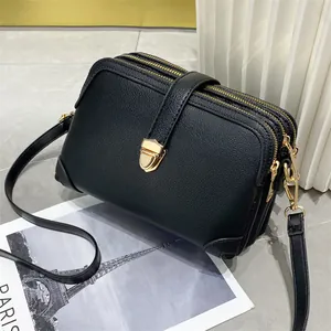 Minimalistische zwarte crossbody tas van leer met drie ritsen en gouden hardware