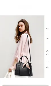 Elegant black lychee leather handbag with decorative silk scarf on handle shown on model