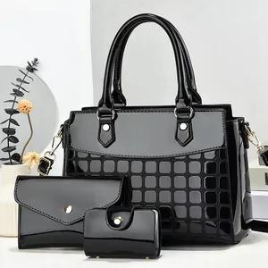 Close-up of three-piece black patent leather handbag set with gold hardware and embossed texture