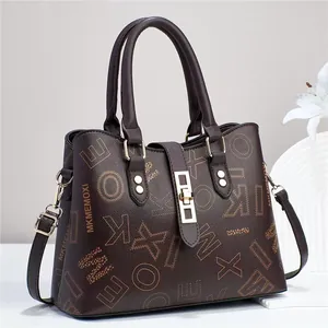 Gros plan sur le cabas en cuir marron foncé avec boucle dorée et imprimé monogramme
