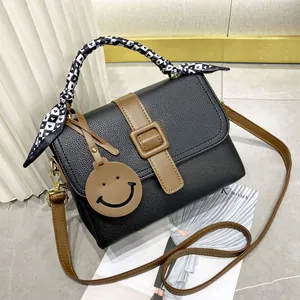 Sac à main chic en cuir grainé noir avec poignée en foulard et pendentif smiley joyeux