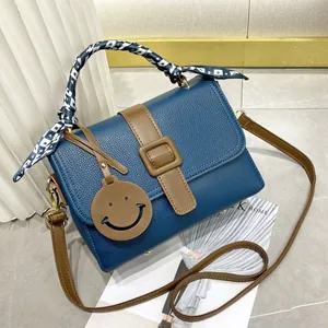 Sac à main bleu en cuir avec foulard, bandoulière marron et boucle dorée chic