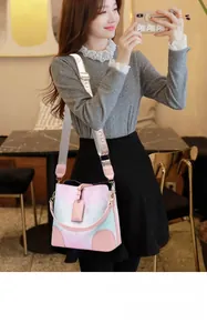 Close-up of pink and blue gradient bucket bag with floral prints and wide jacquard strap