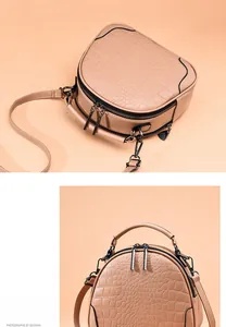 Detail of a beige crocodile pattern crossbody bag with twin zippers and metal hardware