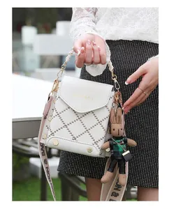 Close-up of white quilted mini crossbody bag with gold studs and rabbit charm