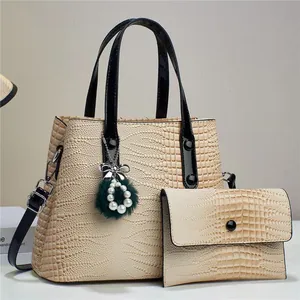 Detailed view of beige crocodile pattern tote bag with luxury charm and black strap