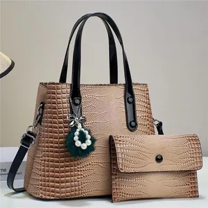 Detail of faux crocodile leather texture and pearl bow charm on brown tote bag
