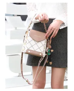 Detail of crossbody bag with beige and brown contrast, rivets and woven rabbit charm
