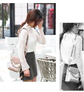 Detail of crossbody bag with quilted diamond pattern, metal chain, and fashion strap