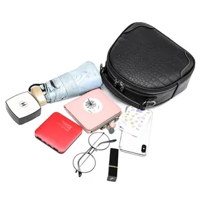 Women's black crocodile texture crossbody bag showing spacious interior with daily items