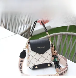 Detail of mini crossbody bag with checkerboard pattern, woven strap, and plush charm