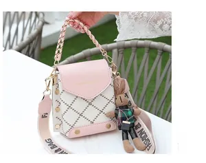 Detail of pink and white crossbody bag with lattice stitching, rivets and rabbit charm