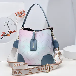 Gradient rainbow bucket bag with floral patterns and a wide woven shoulder strap