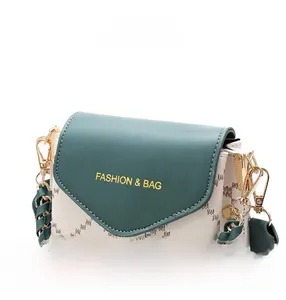Detail shot of mini crossbody bag showing green leather flap and gold fashion stamping