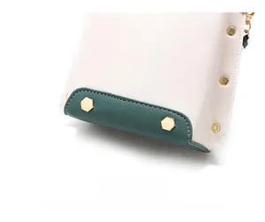 Detailed close-up of white textured bag with green piping and gold hexagonal rivets