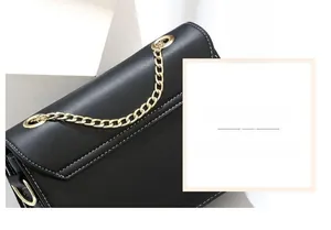 Détail du petit sac carré noir avec chaîne dorée et coutures contrastées blanches