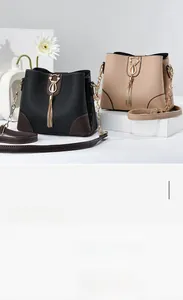 Detailed view of bucket bag with gold cat-shaped hardware and elegant metal tassels