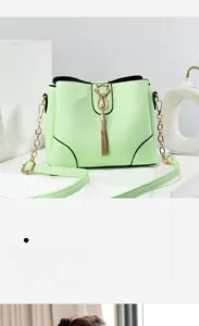 Detail of mint green bucket bag with gold cat charm and elegant tassel ornament