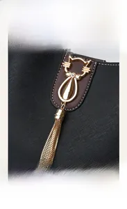 Detailed macro view of the golden cat-shaped metal clasp on a black cross-grain leather bag