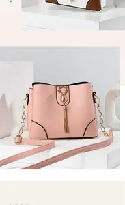 Detail of pink PU leather bucket bag with gold cat buckle, fringe tassel and chain strap