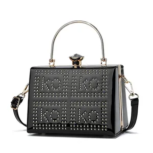 Detail of black patent leather handbag featuring gold rivet logo and crystal clasp
