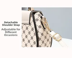 Detail of detachable shoulder strap with light gold D-ring hardware on printed cream handbag