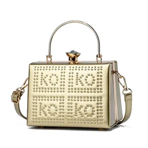 Close-up of golden hard shell evening bag with KOKO rivet lettering and jewel clasp