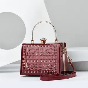 Macro view of burgundy patent leather evening bag with golden rivets and diamond clasp