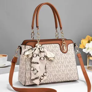 Detail einer braunen Handtasche mit Monogramm-Muster und dekorativem Seidenschal-Akzent