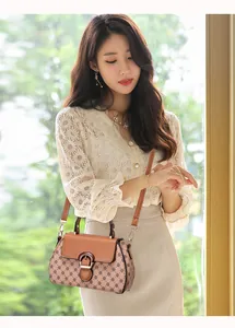Close-up of brown textured leather flap with golden clasp on crossbody bag